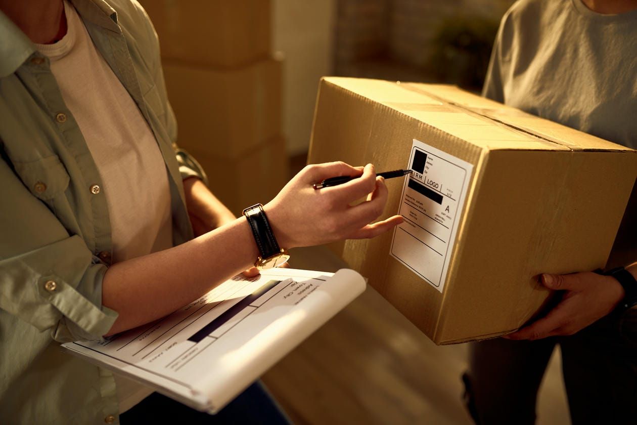 Two delivery women cooperating while checking data on the packages in the office