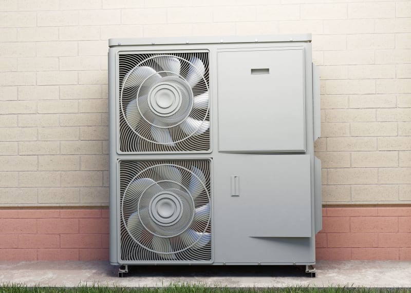 Traditional air source heat pump with visible outdoor fan unit mounted on exterior wall