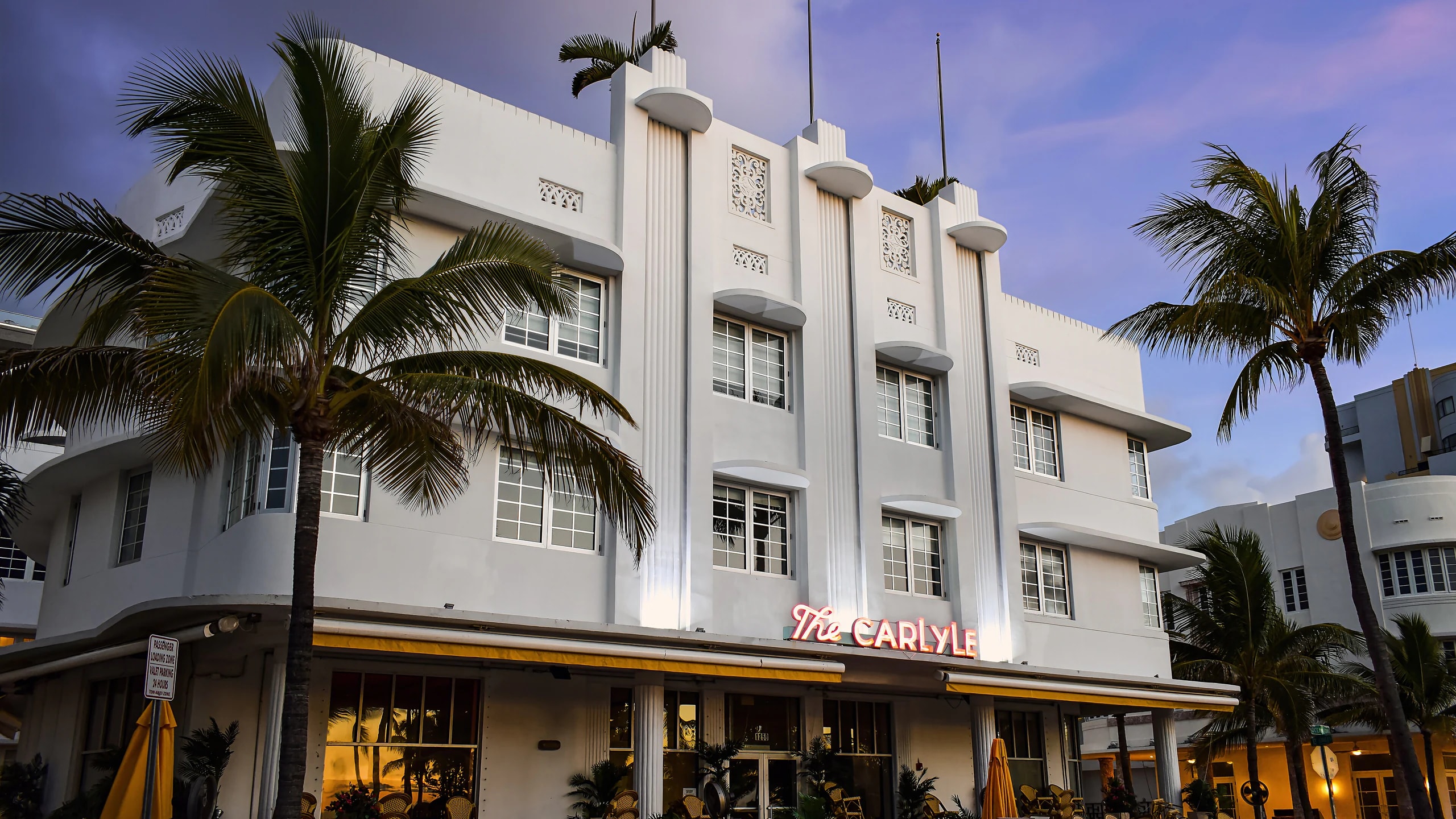 The Carlyle hotel framed by palm trees at dusk