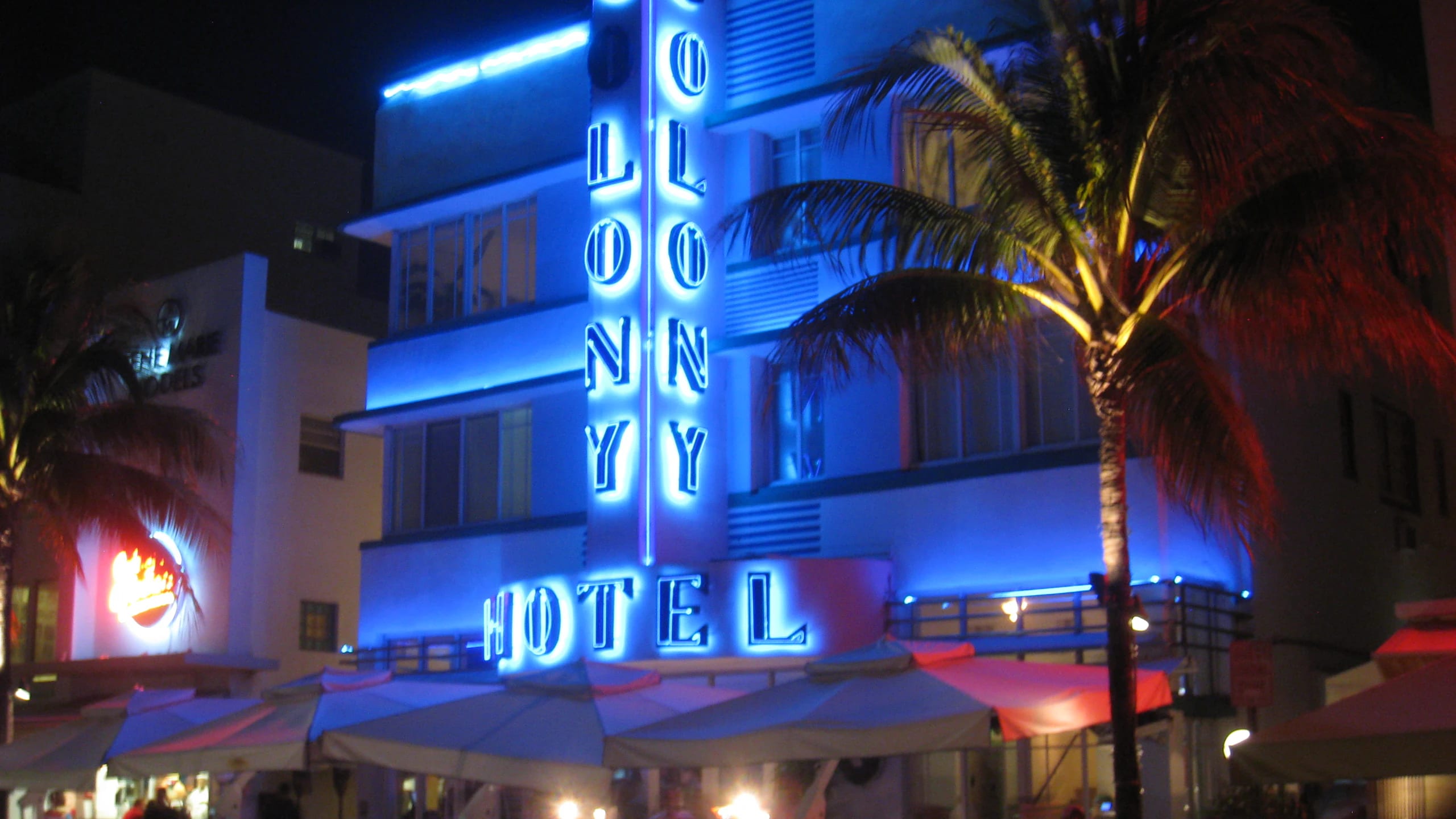 The Colony Hotel's blue neon sign glowing at night on Ocean Drive