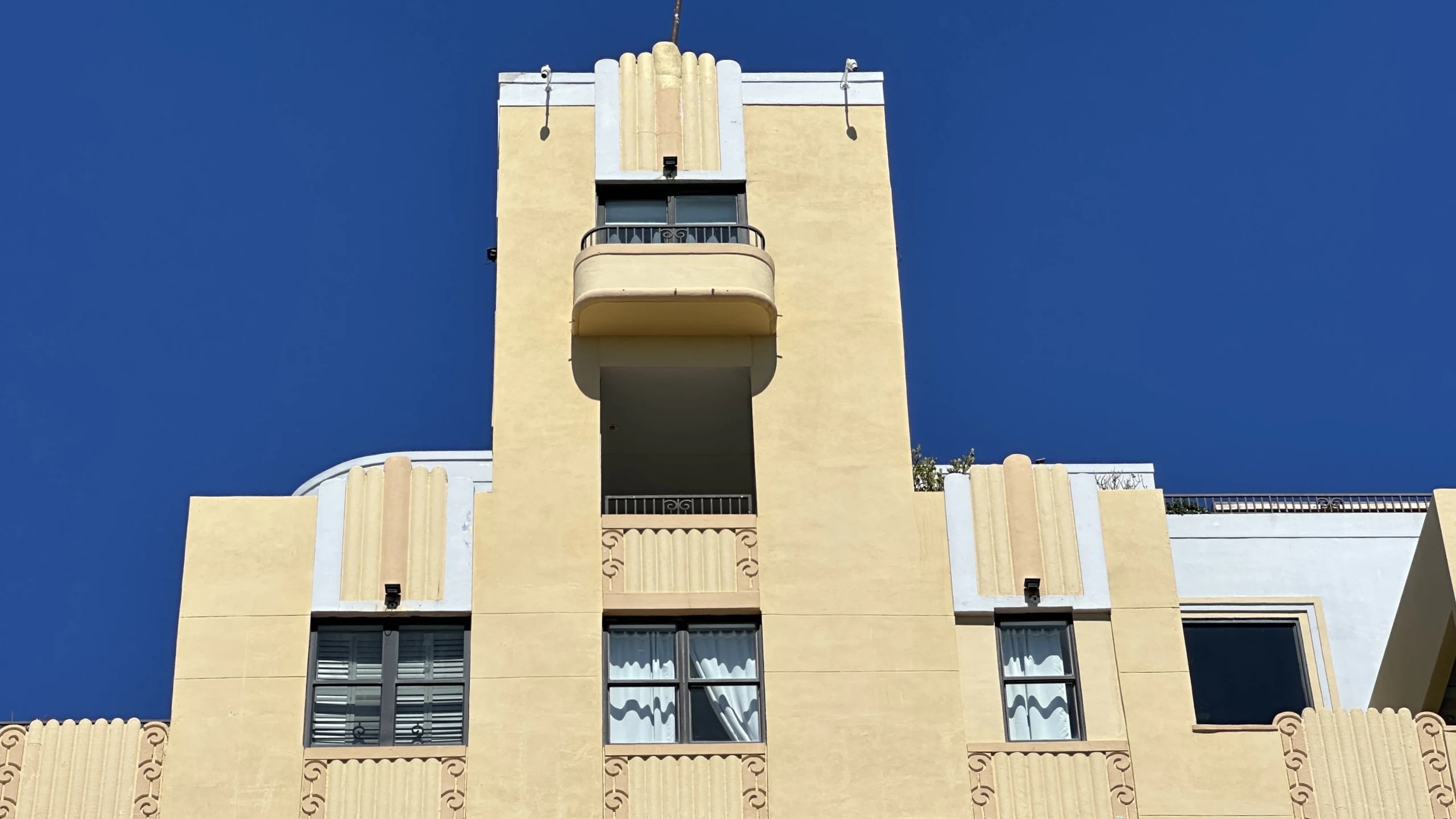 A cream art deco hotel tower under a deep blue sky