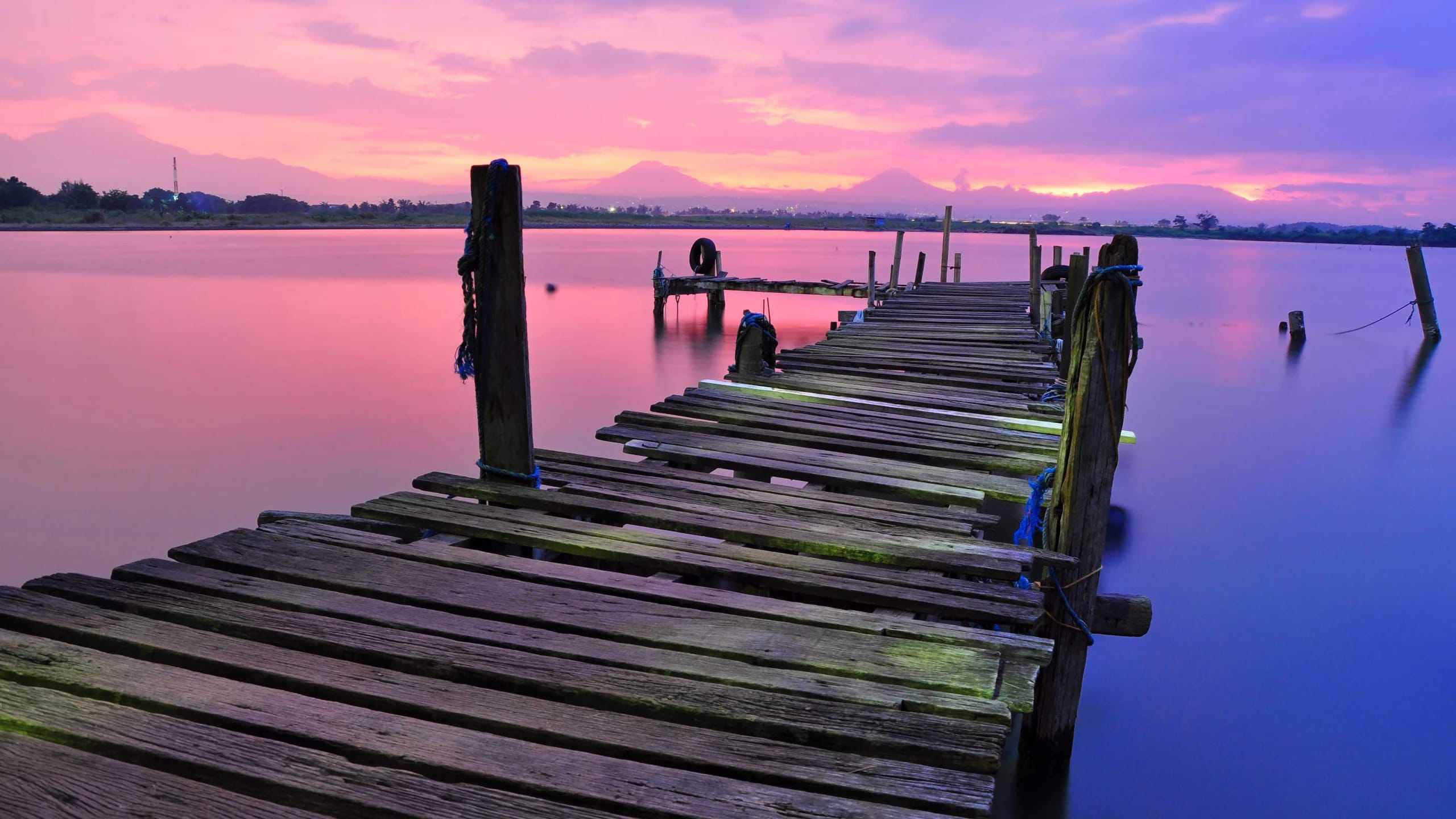 An old wooden pier at a pink and purple sunset