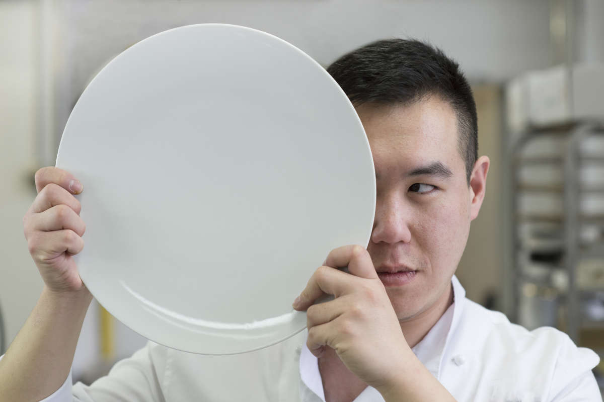 Portrait of Chef Park Min-jae plating a dish in formal whites