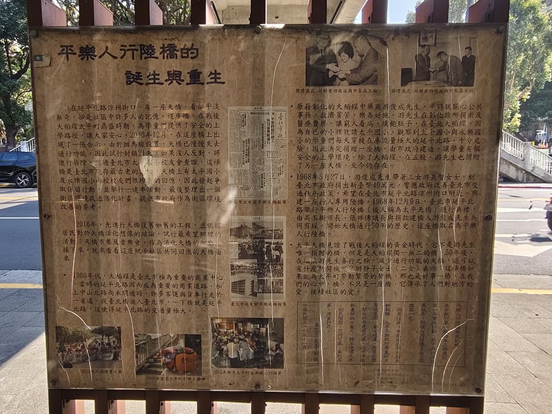 平樂人行陸橋底下的解說牌，經過長期日曬，顯得斑駁。上面有老照片和報導，讓民眾經過時可以了解這座橋的歷史。（圖/張復嘉攝影）
