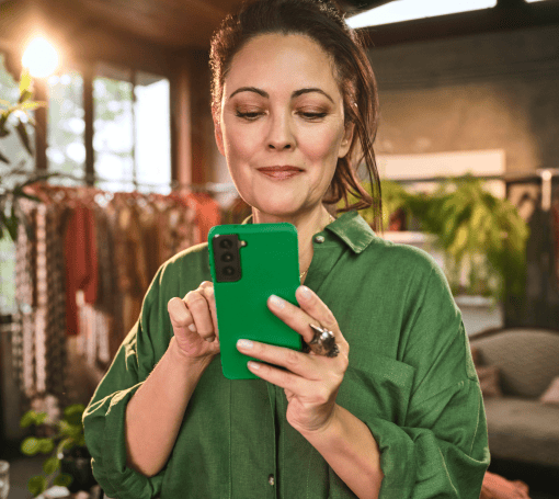 Empreendedora segurando o celular para utilizar o link de pagamento Stone em sua loja de roupas