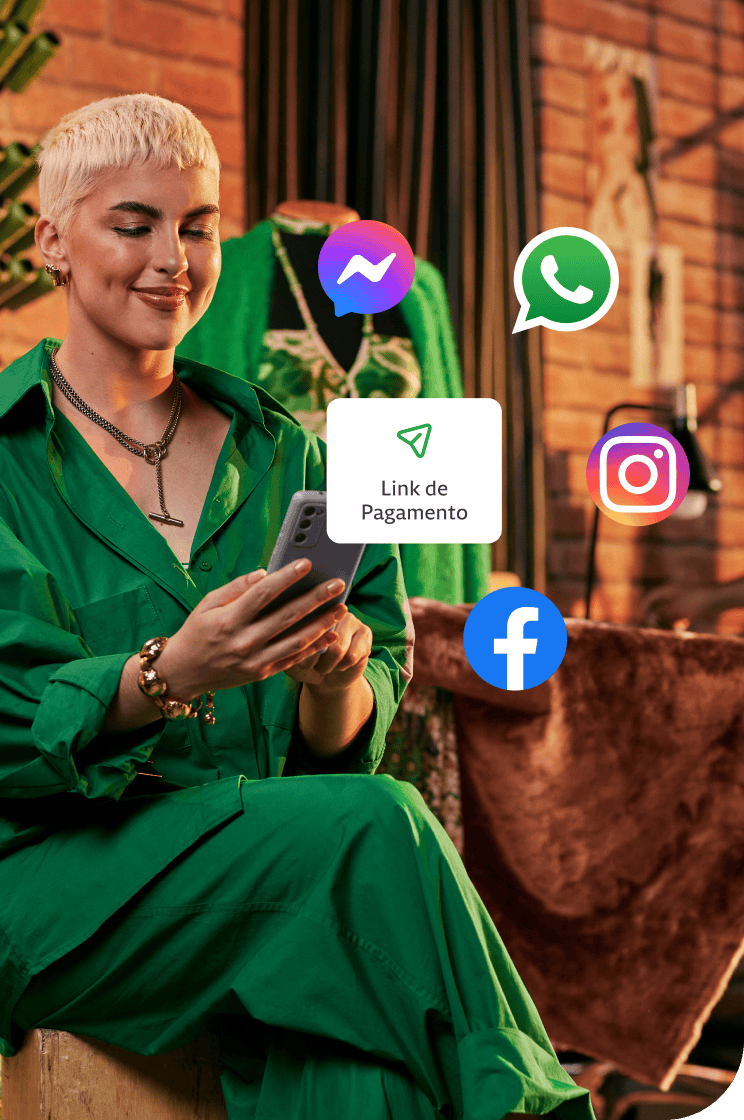 Empreendedora em sua loja segurando o seu celular, atrás algumas linhas de costuras penduradas na parede e um manequim. Além disso, um balão de Link de Pagamento com ícones do Messenger, Whatsapp, Instagram e Facebook em volta.