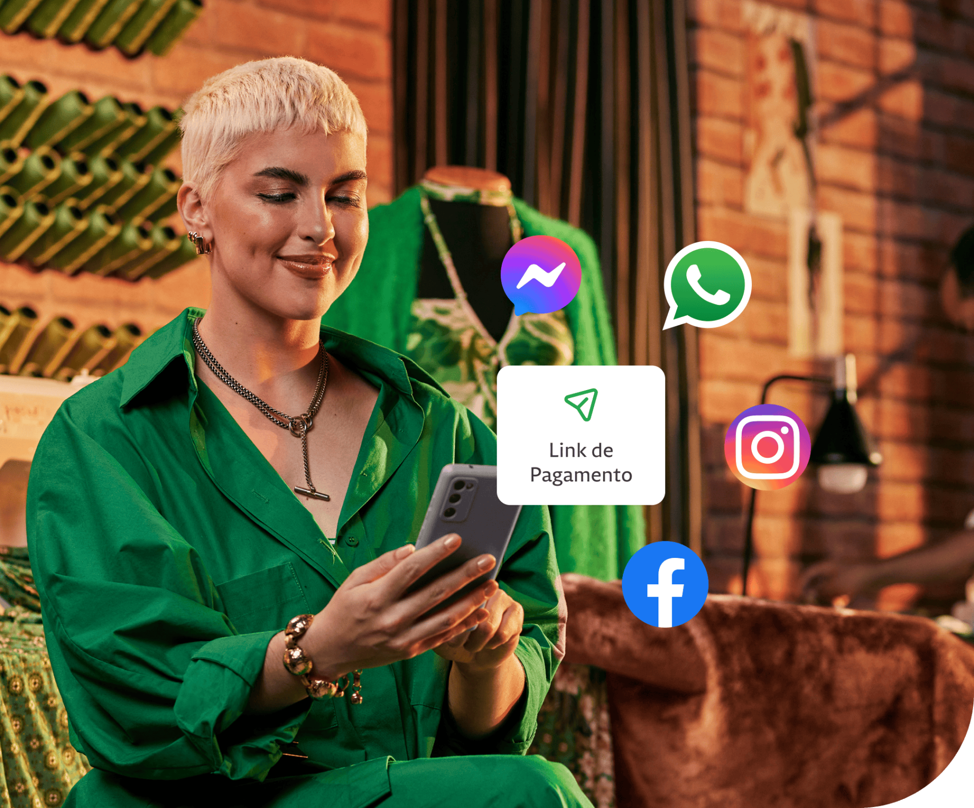 Empreendedora em sua loja segurando o seu celular, atrás algumas linhas de costuras penduradas na parede e um manequim. Além disso, um balão de Link de Pagamento com ícones do Messenger, Whatsapp, Instagram e Facebook em volta.