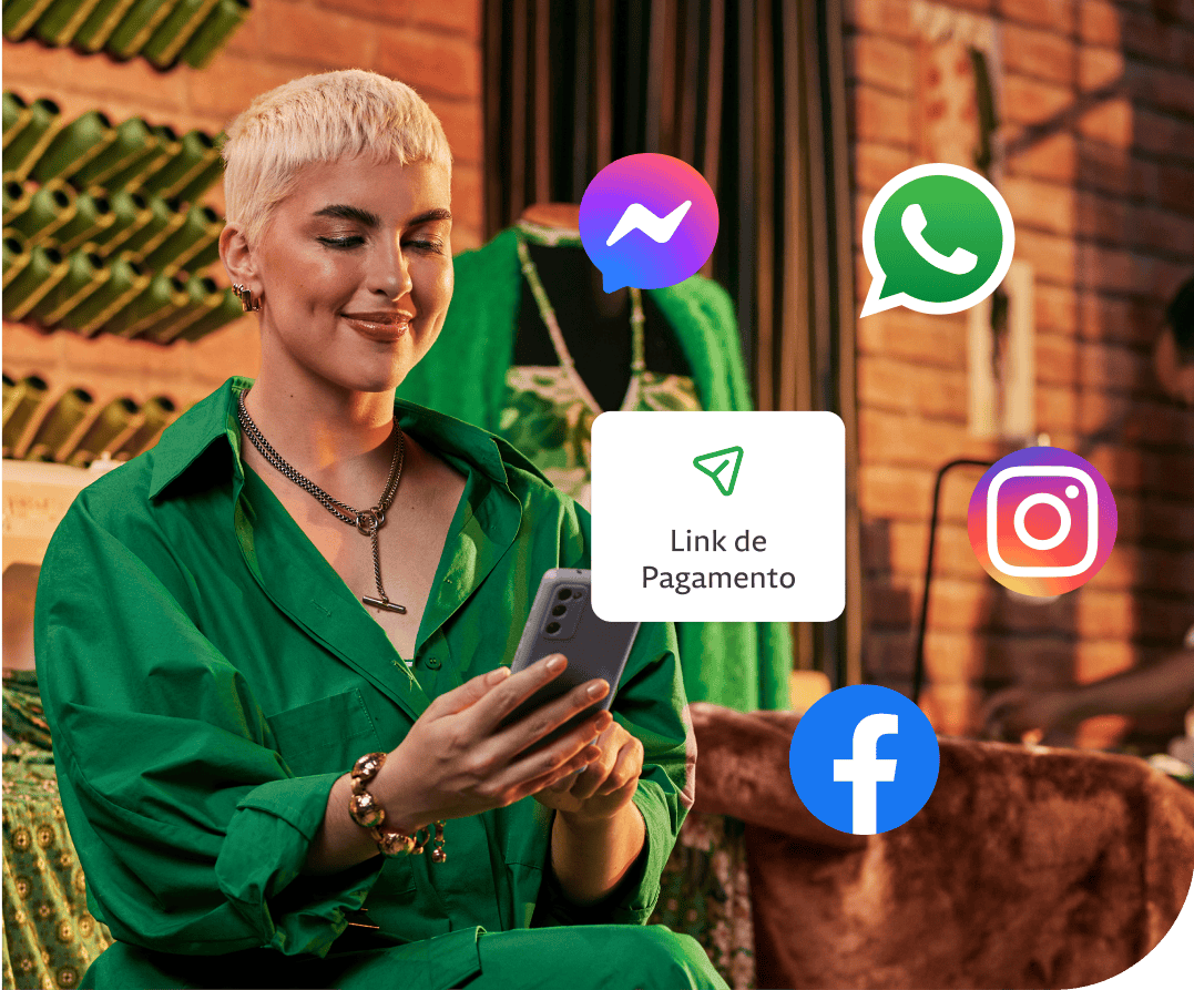 Empreendedora em sua loja segurando o seu celular, atrás algumas linhas de costuras penduradas na parede e um manequim. Além disso, um balão de Link de Pagamento com ícones do Messenger, Whatsapp, Instagram e Facebook em volta.