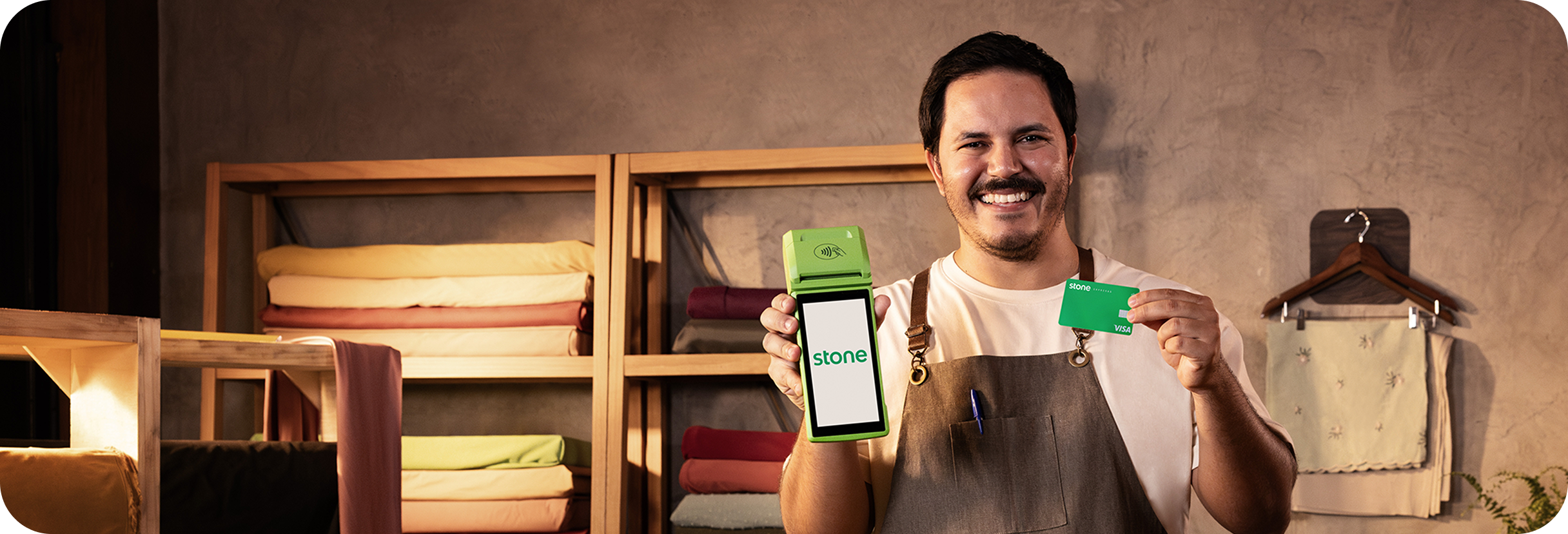 Empreendedor segurando a sua máquina de cartão da Stone e o seu cartão Stone.