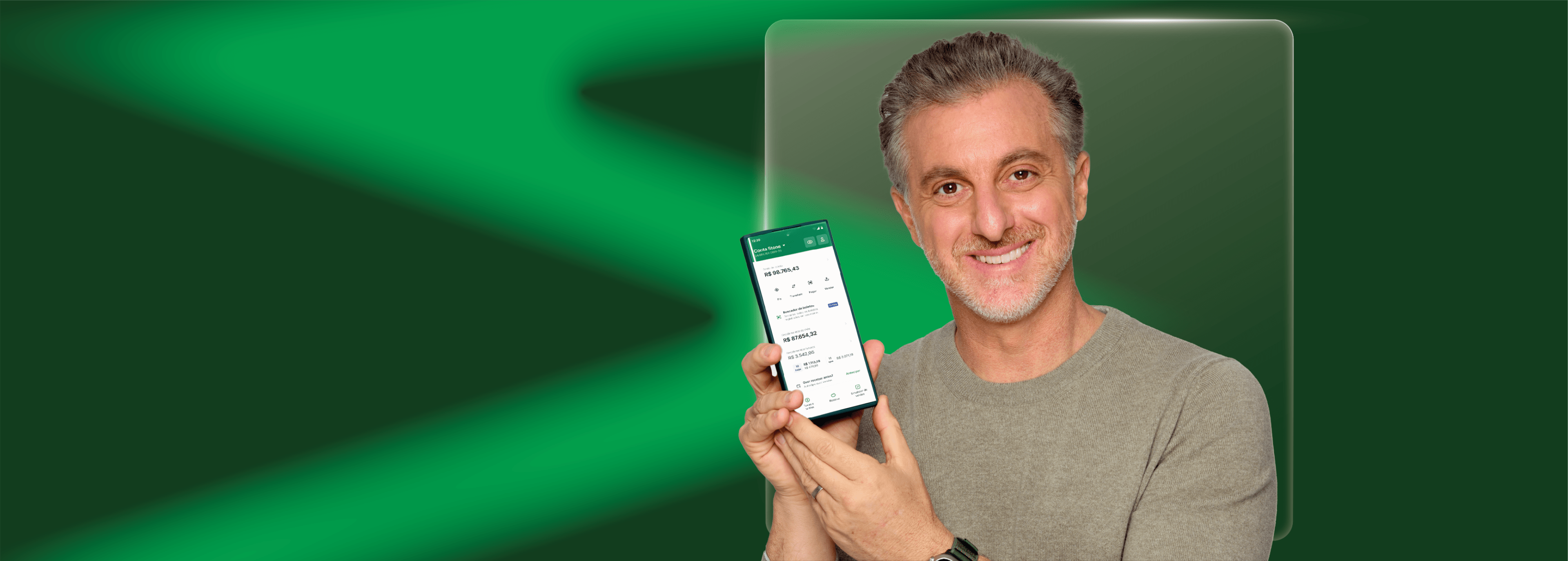 Luciano Huck segurando um celular com o aplicativo da Stone