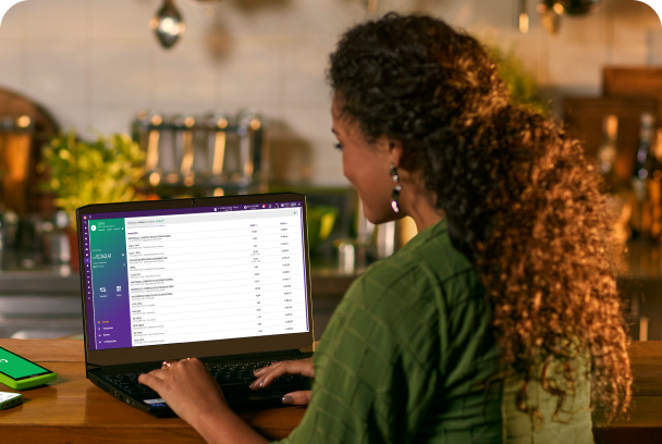 Mulher sentada usando um sistema da Linx em um notebook