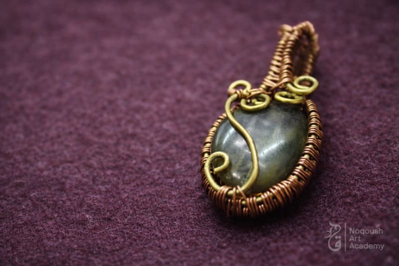Copper wire-wrapped pendant featuring a dark green oval stone and spiral details.