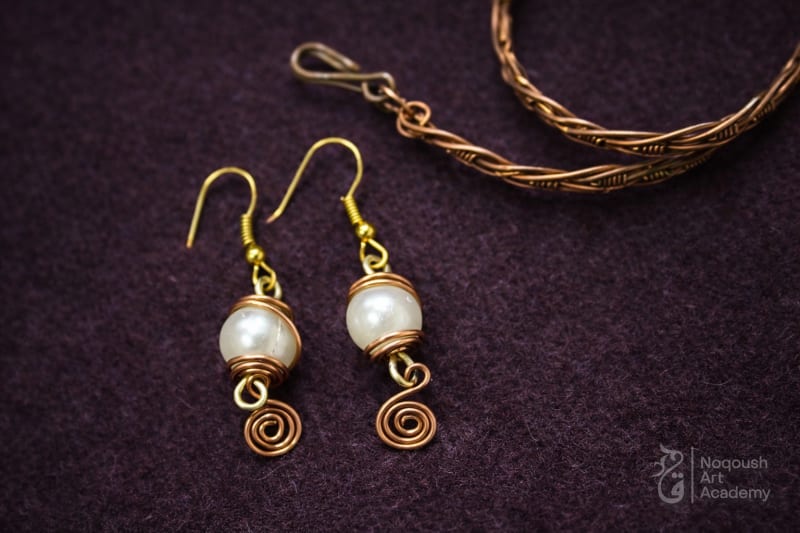 Pair of gold wire-wrapped pearl earrings with spiral details.