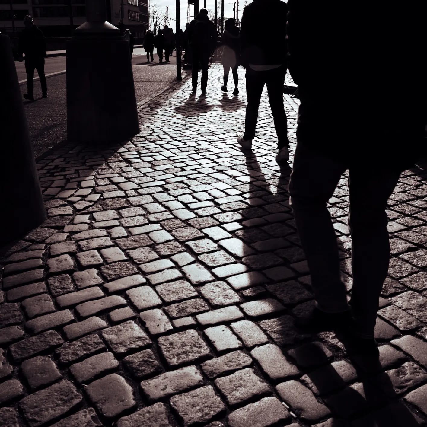 Shadows of walkers on a cobblestone street at night