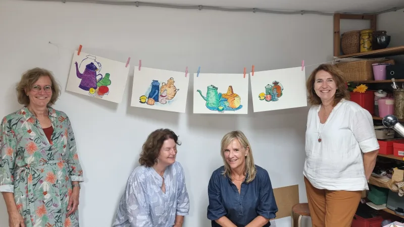 Deelnemers aan een creatieve workshop in een licht atelier, gefocust op schilderen en kunst maken.