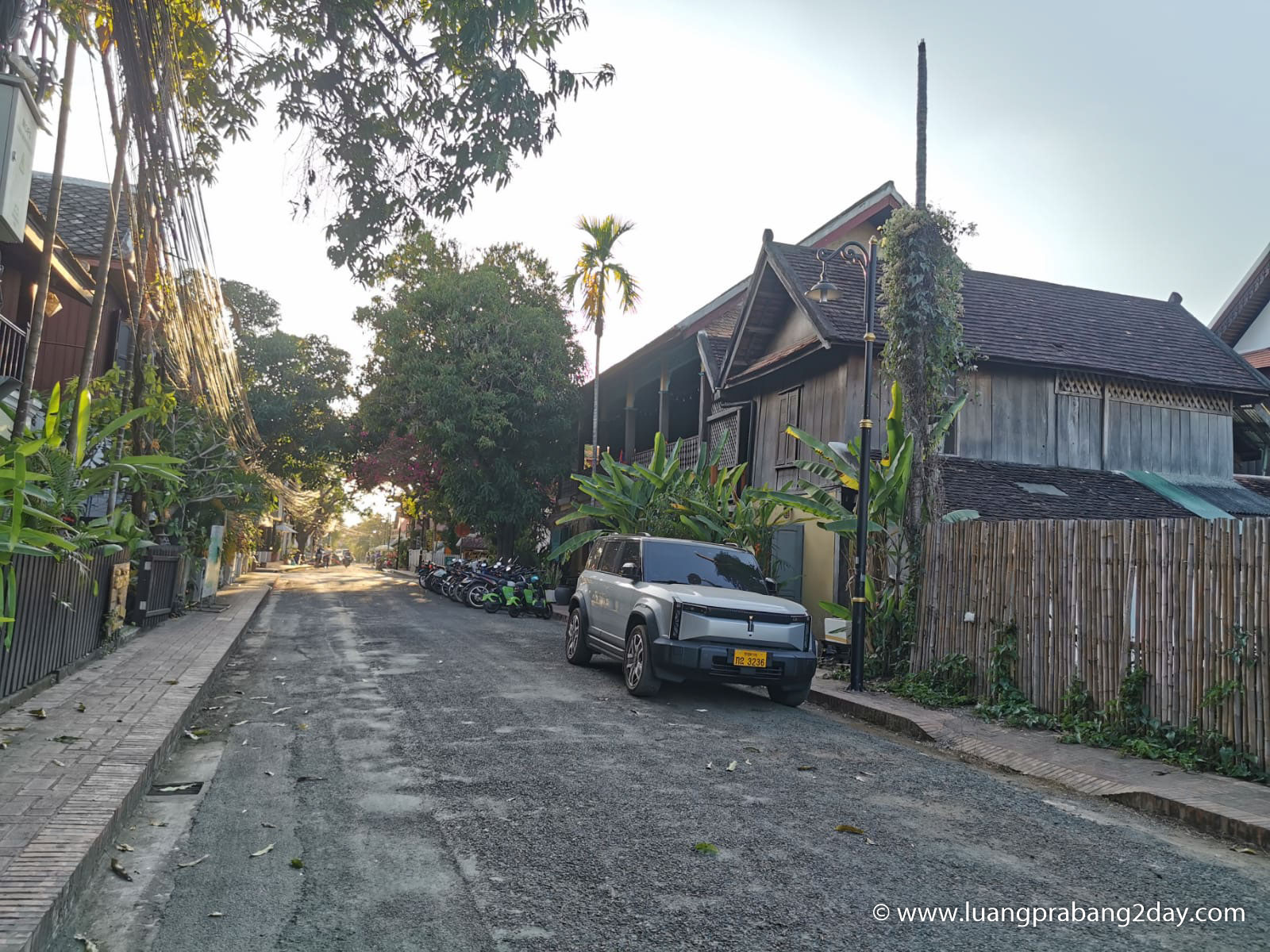 A quiet residential street in Luang Prabang with traditional wooden houses, reflecting everyday cultural continuity and stable urban life A quiet residential street in Luang Prabang with traditional wooden houses, reflecting everyday cultural continuity and stable urban life