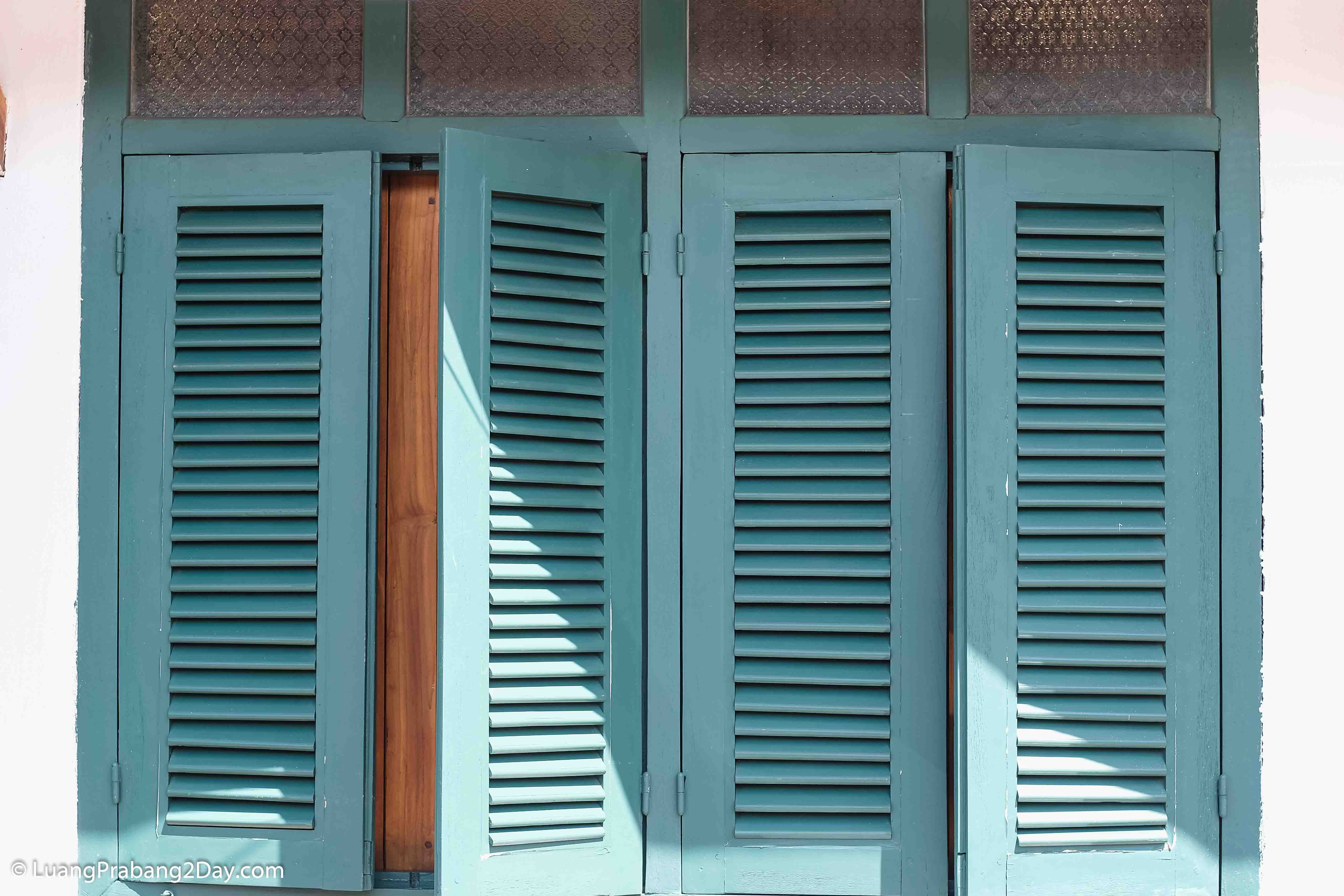 Traditional wooden shutters partially open on a heritage house in Luang Prabang, reflecting the city's enduring architectural identity and everyday cultural heritage. Traditional wooden shutters partially open on a heritage house in Luang Prabang, reflecting the city's enduring architectural identity and everyday cultural heritage.