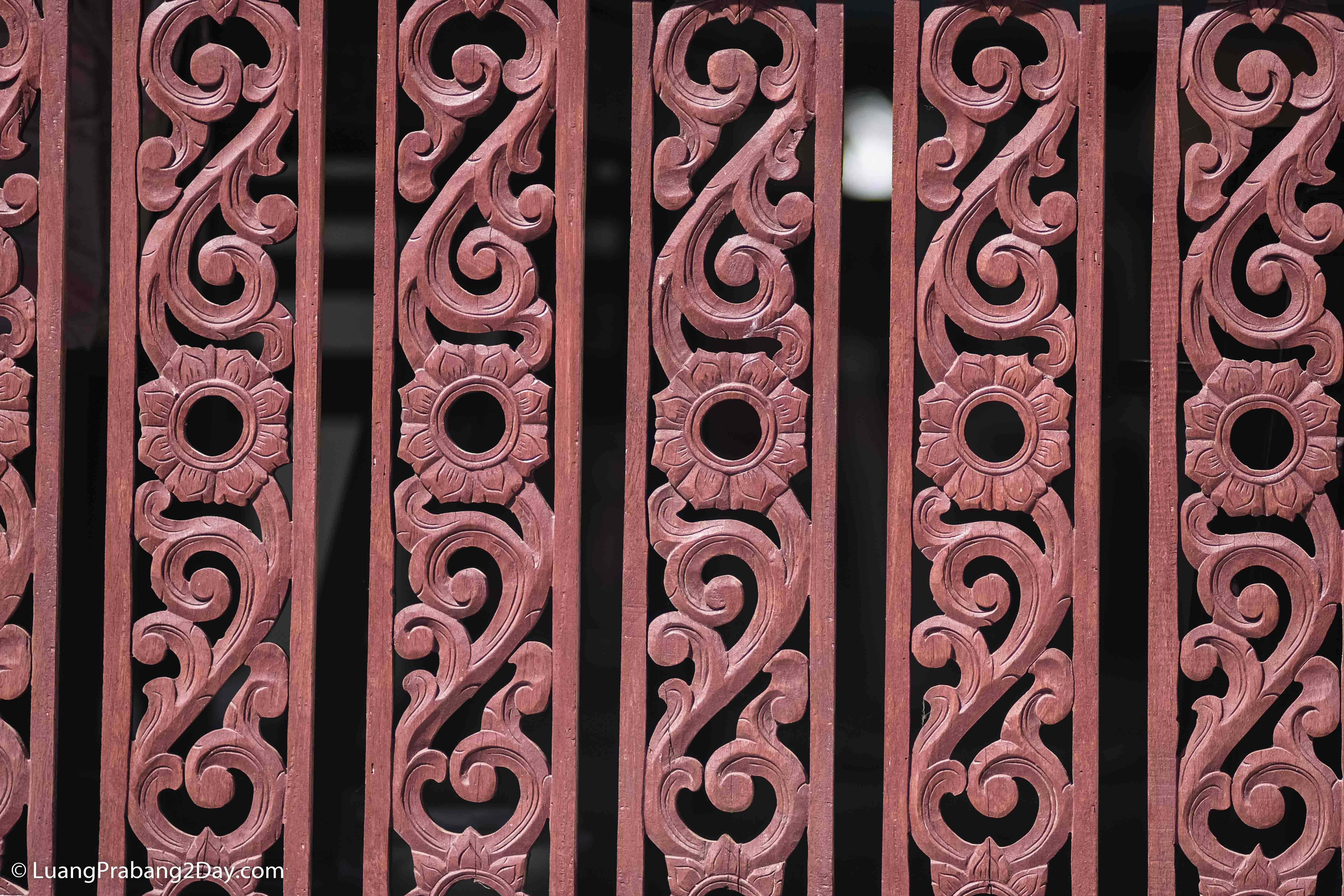 Intricately carved wooden balustrade displaying floral motifs inspired by traditional Lao craftsmanship. Intricately carved wooden balustrade displaying floral motifs inspired by traditional Lao craftsmanship.