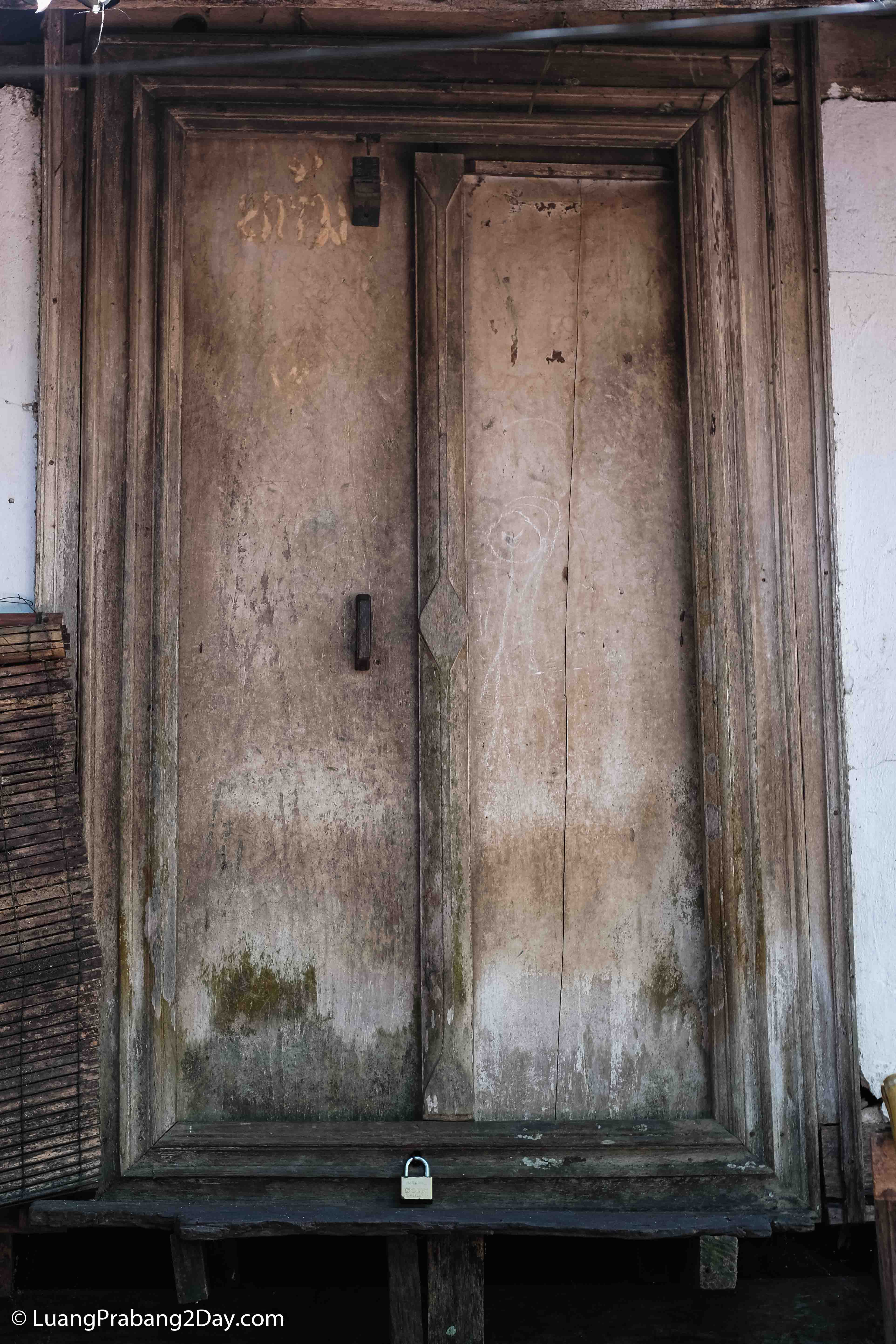Weathered wooden door with an iron ring handle showing decades of natural aging and everyday use. Weathered wooden door with an iron ring handle showing decades of natural aging and everyday use.