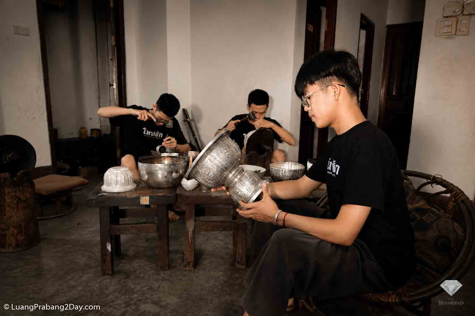 Several young craftsmen work together inside a traditional silver workshop in Luang Prabang, each performing a different stage of handmade silver production. Several young craftsmen work together inside a traditional silver workshop in Luang Prabang, each performing a different stage of handmade silver production.