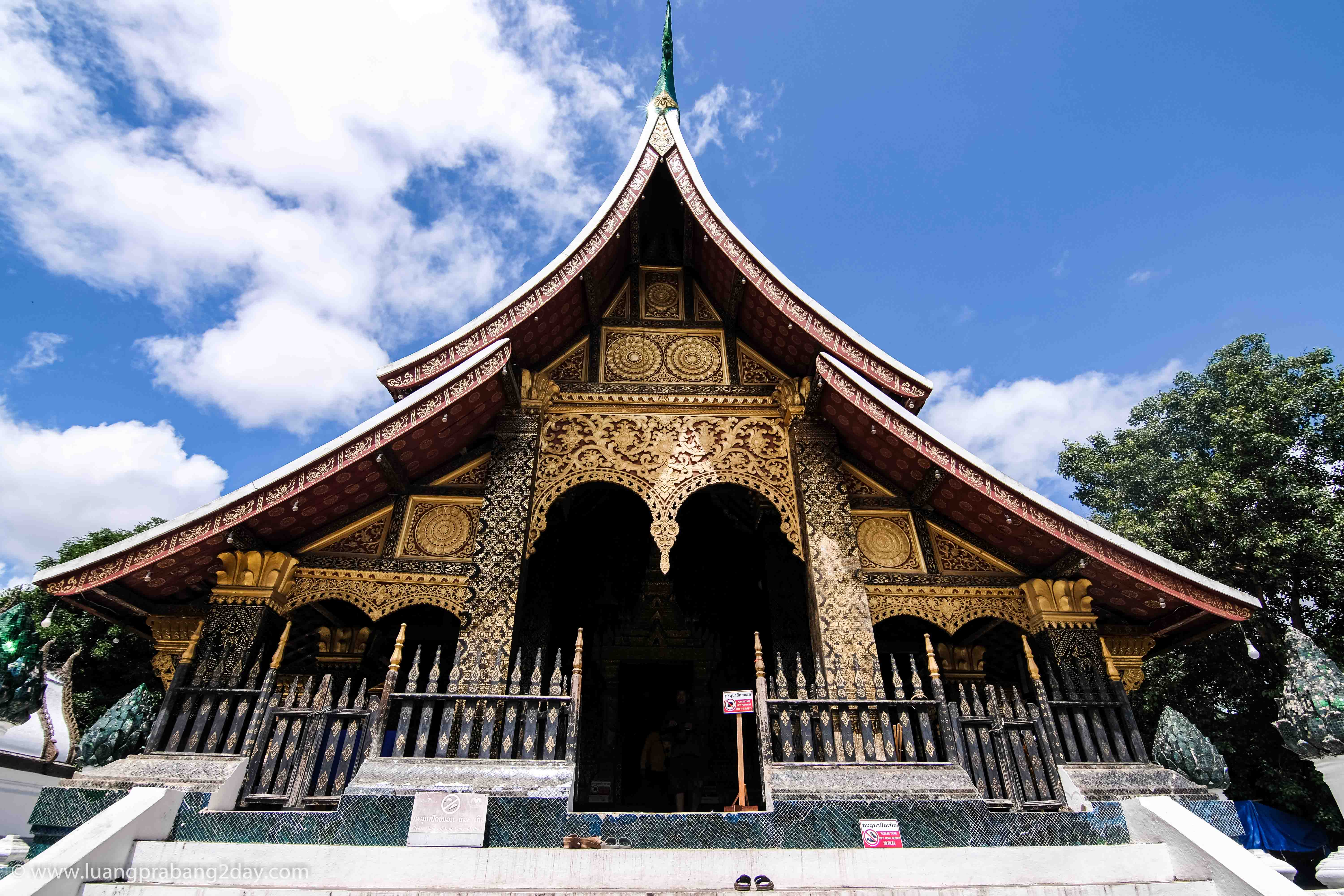 Main façade of Wat Xieng Thong featuring gilded carvings beneath layered temple roofs. Main façade of Wat Xieng Thong featuring gilded carvings beneath layered temple roofs.