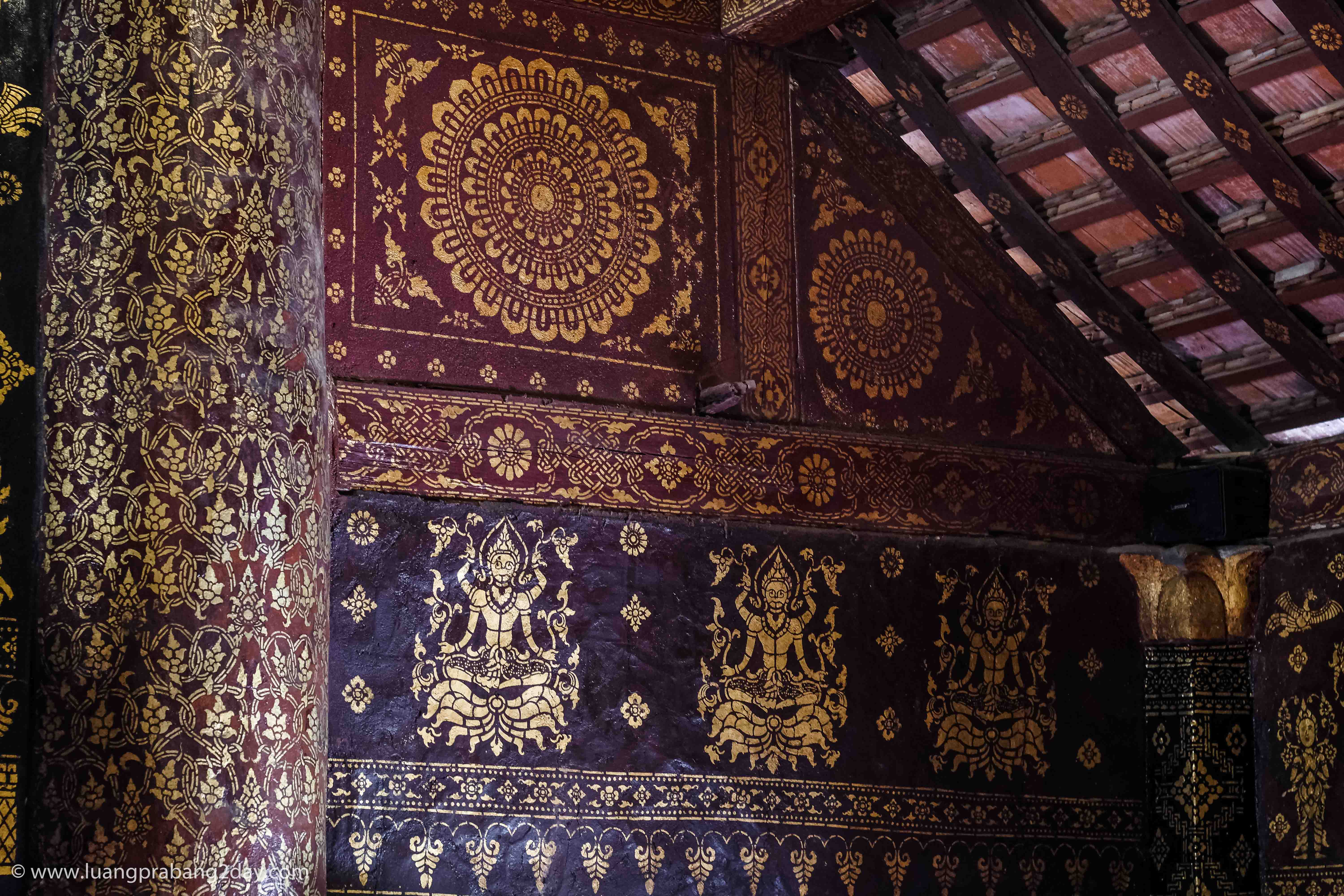 Interior wall of Wat Xieng Thong featuring floral gilded motifs beneath the traditional wooden roof. Interior wall of Wat Xieng Thong featuring floral gilded motifs beneath the traditional wooden roof.