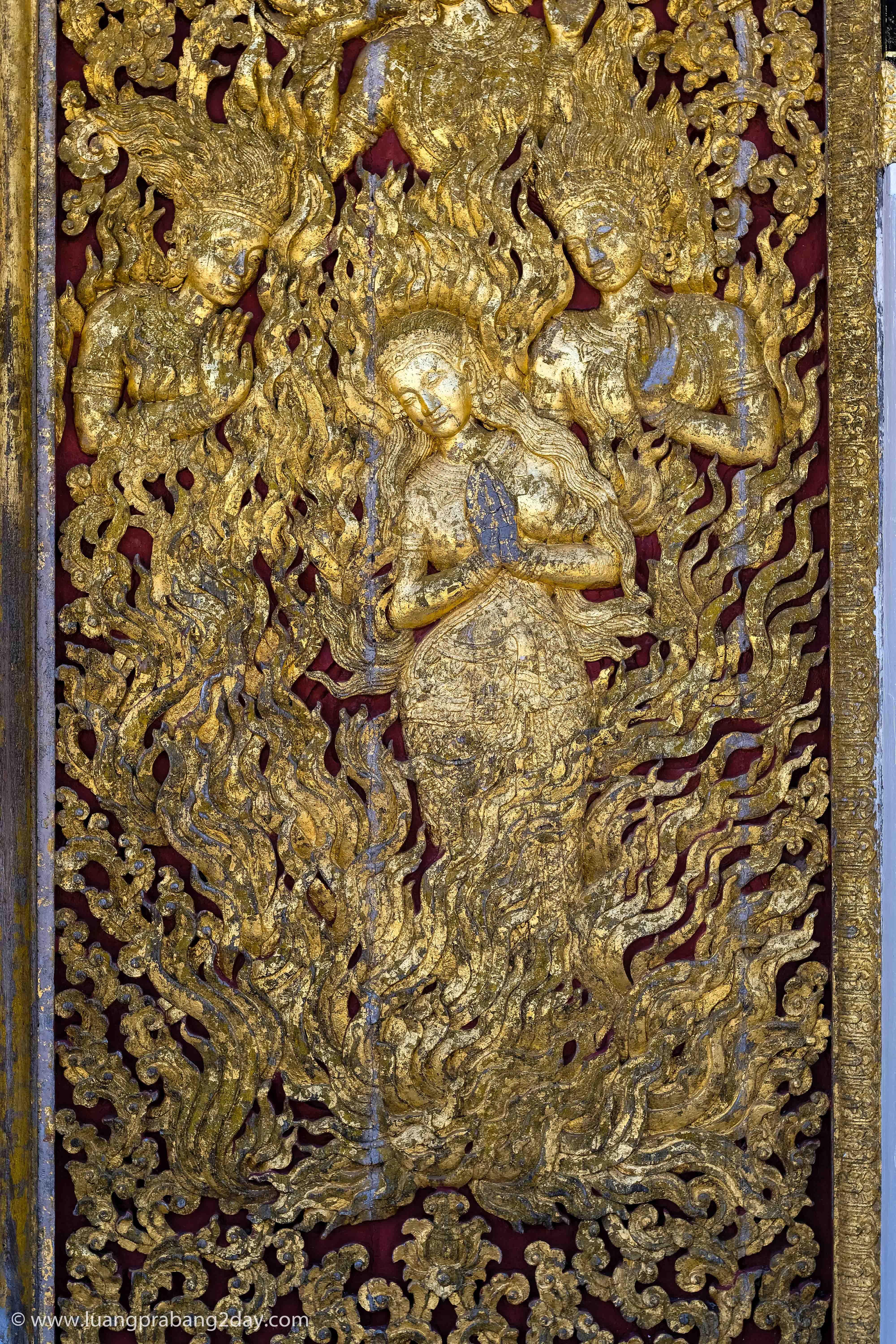 Intricately carved gilded relief panel depicting a celestial figure inside Wat Xieng Thong. Intricately carved gilded relief panel depicting a celestial figure inside Wat Xieng Thong.