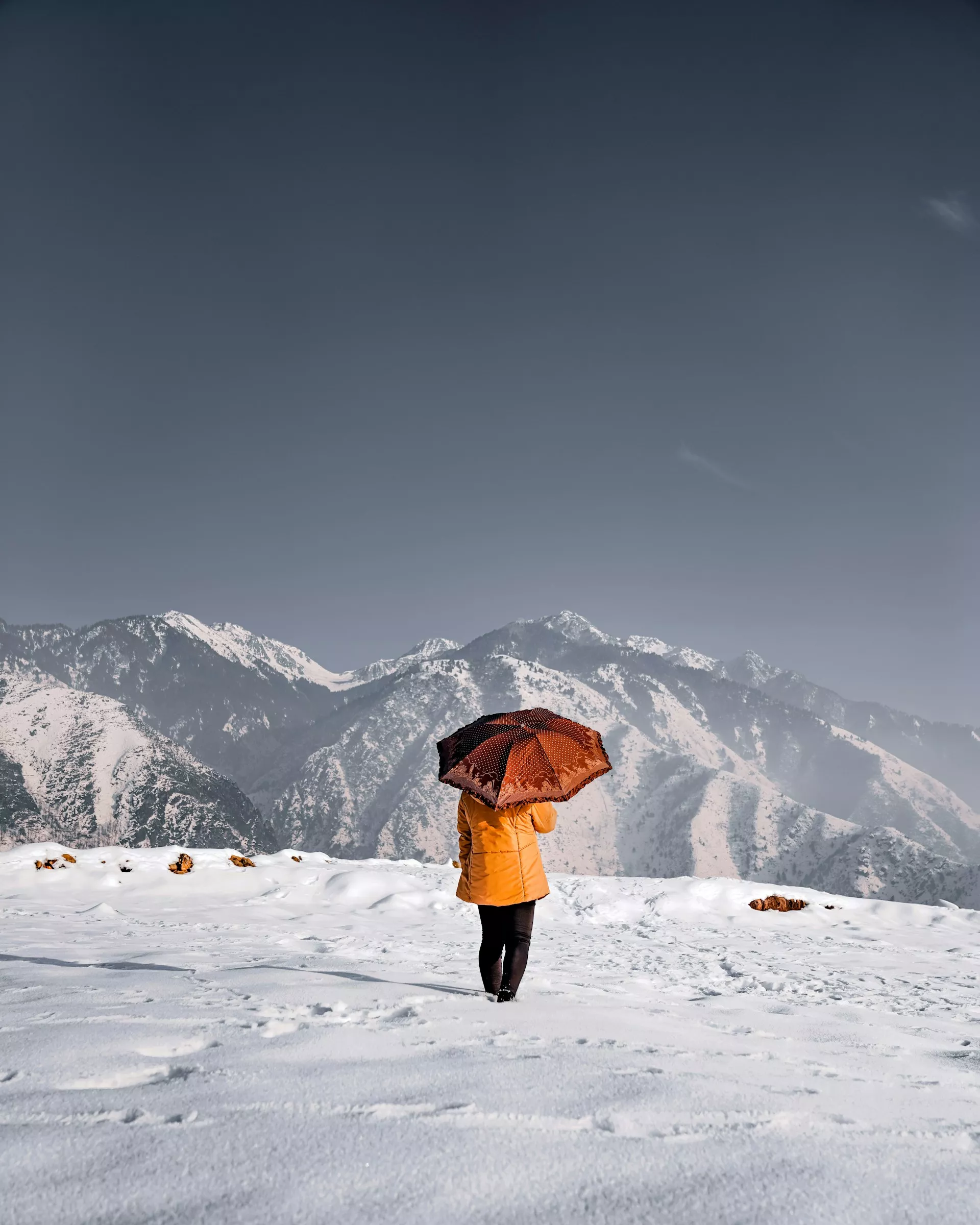 Girl with an umbrella surrounded by snowy mountains in Kashmir