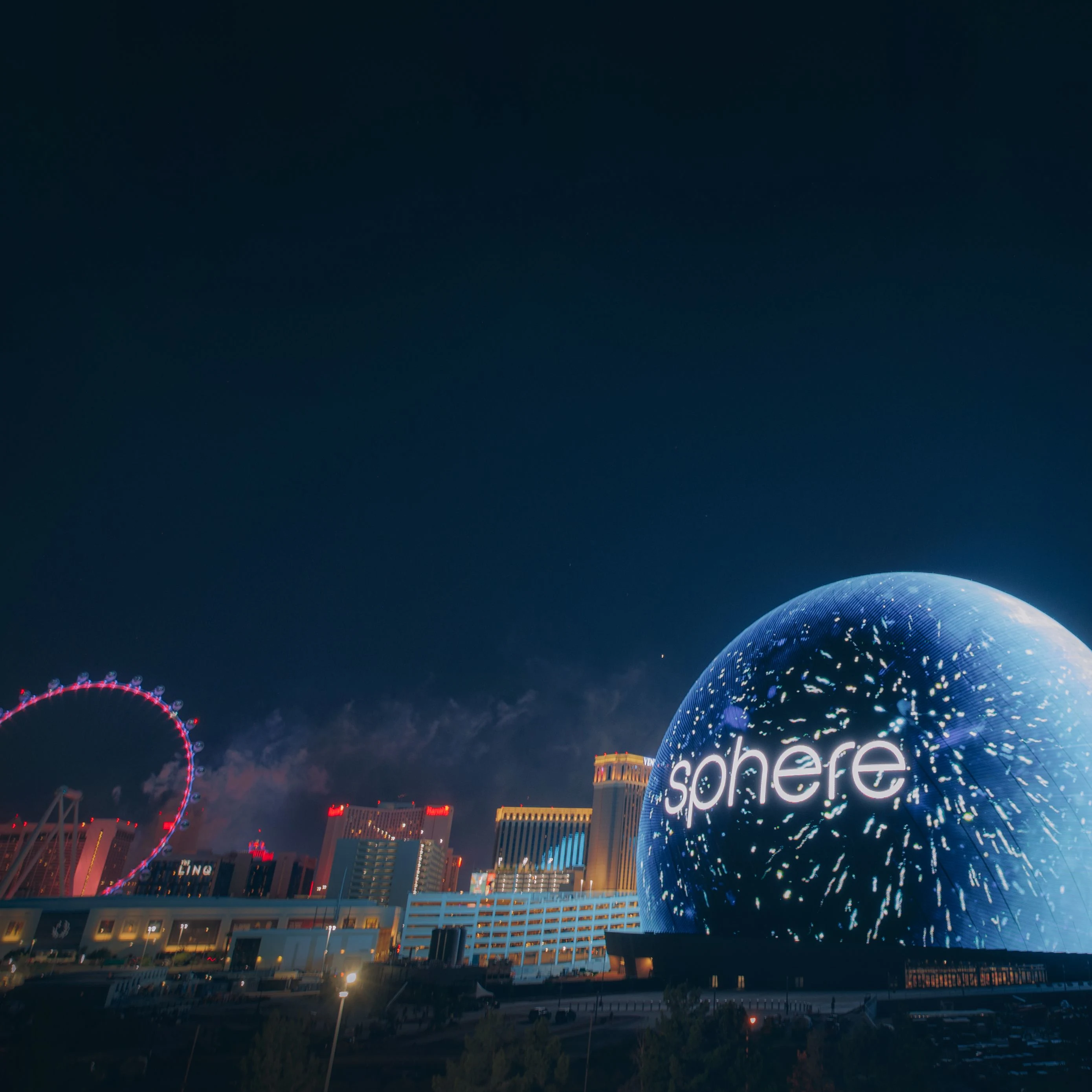 High-resolution exterior view of the Las Vegas Sphere illuminated at night, showcasing its fully lit LED display in vibrant colors.