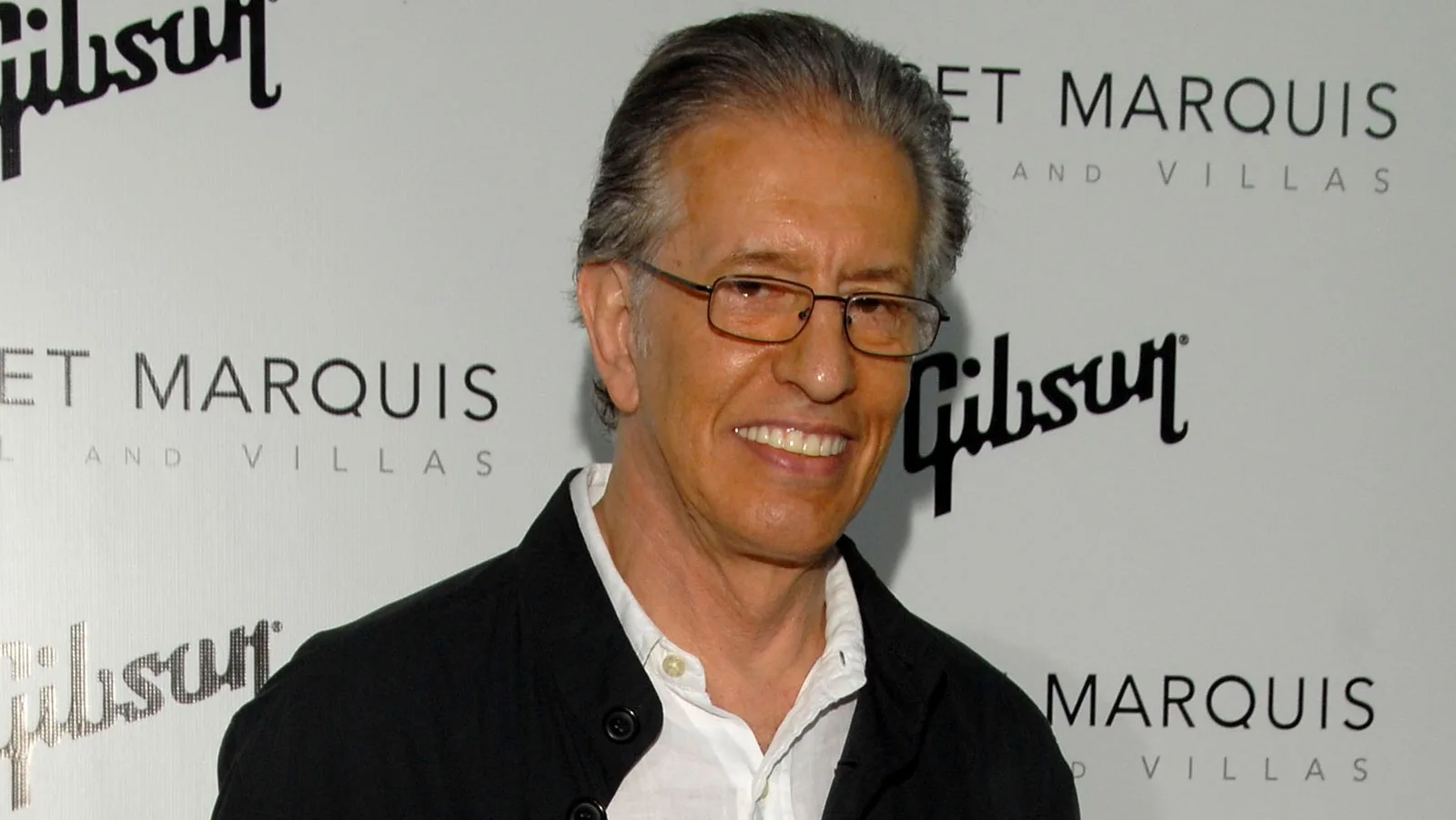 Professional medium-shot of Richard Perry outdoors, looking off camera, likely at an event.