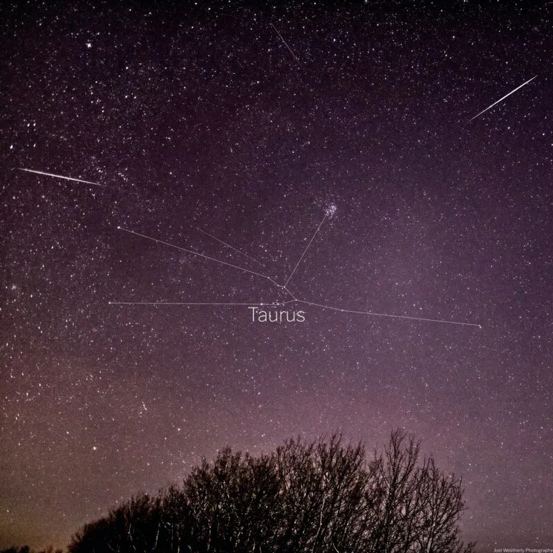 A crisp, high-quality night-sky photograph showing a meteor streaking through the constellation Taurus, taken from a dark-sky location.