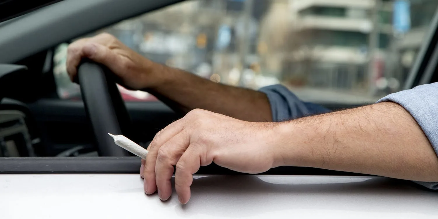 High-quality, text-free image showing a car on a road at night with a marijuana leaf, symbolizing the intersection of driving and cannabis use.