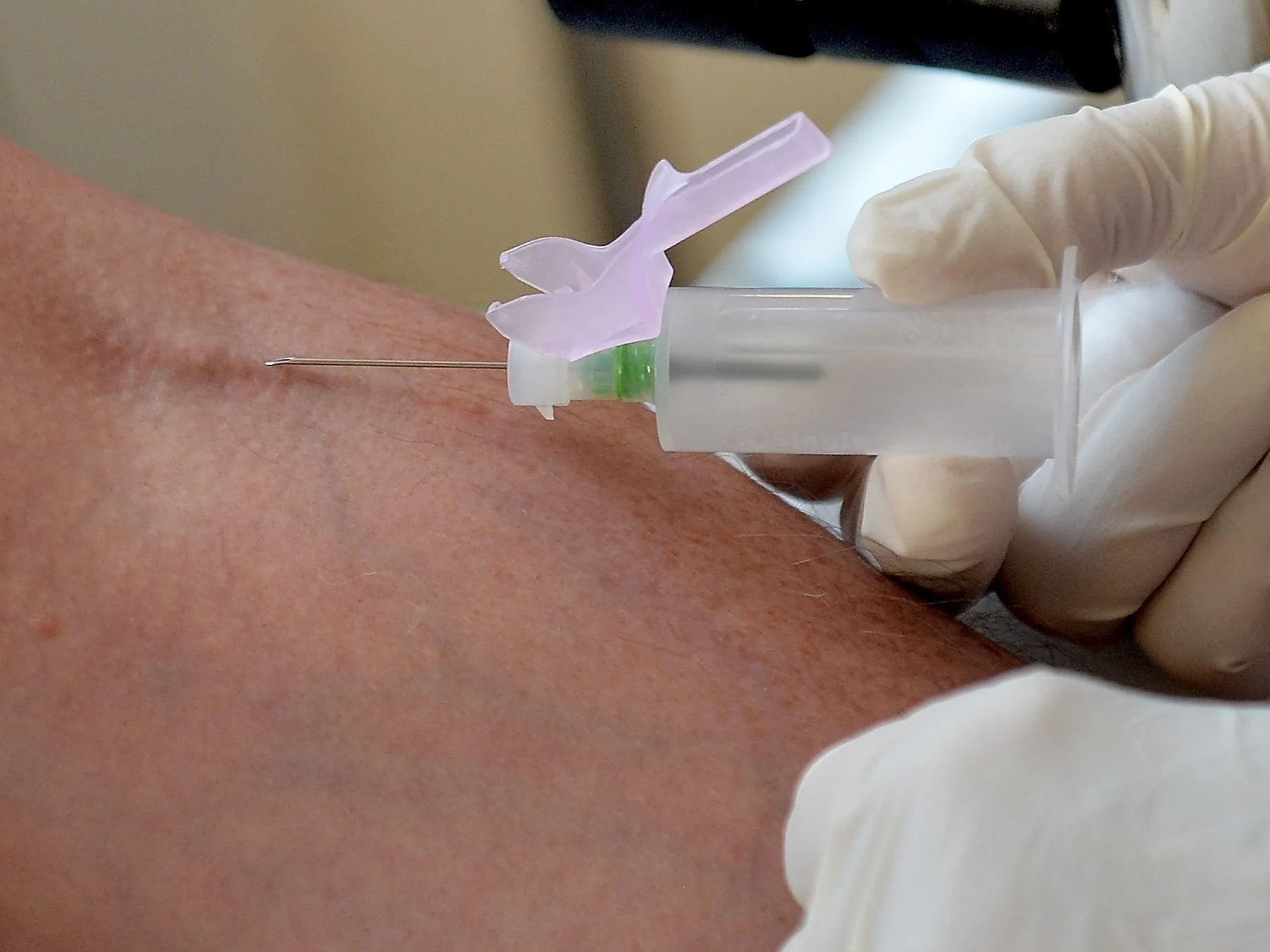 Close-up of a blood draw, focusing on the medical professional’s gloved hands and needle, suitable for illustrating medical diagnostics.