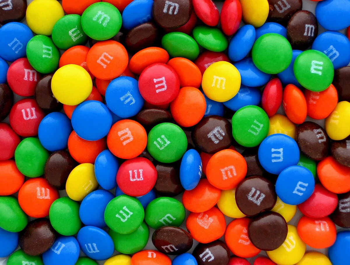 A high-quality close-up image of a colorful pile of plain M&Ms, clearly showcasing the iconic candy without any distracting elements or text.