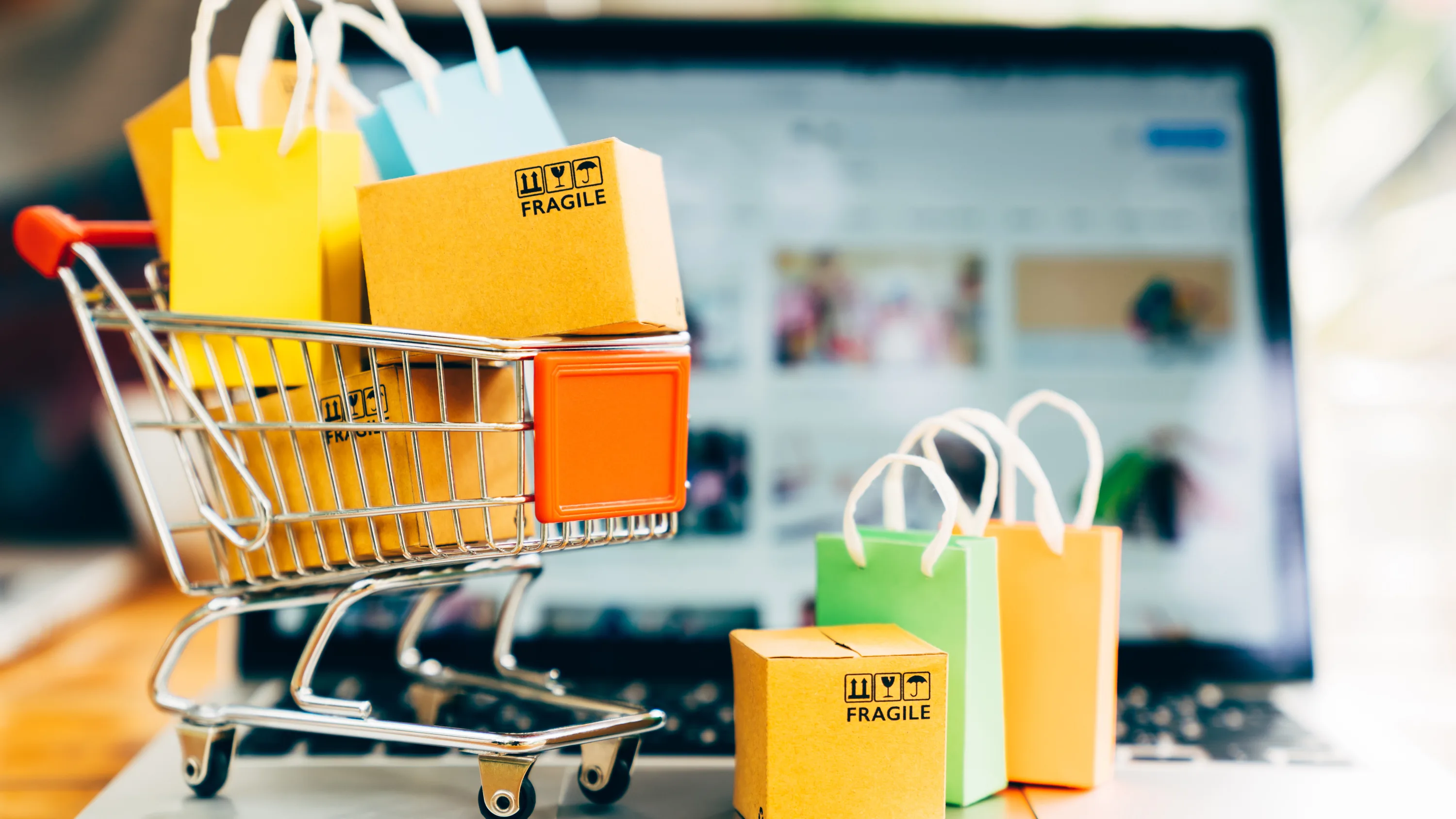 Digitally rendered image of a shopping cart emerging from a laptop screen, symbolizing e-commerce and online deals.