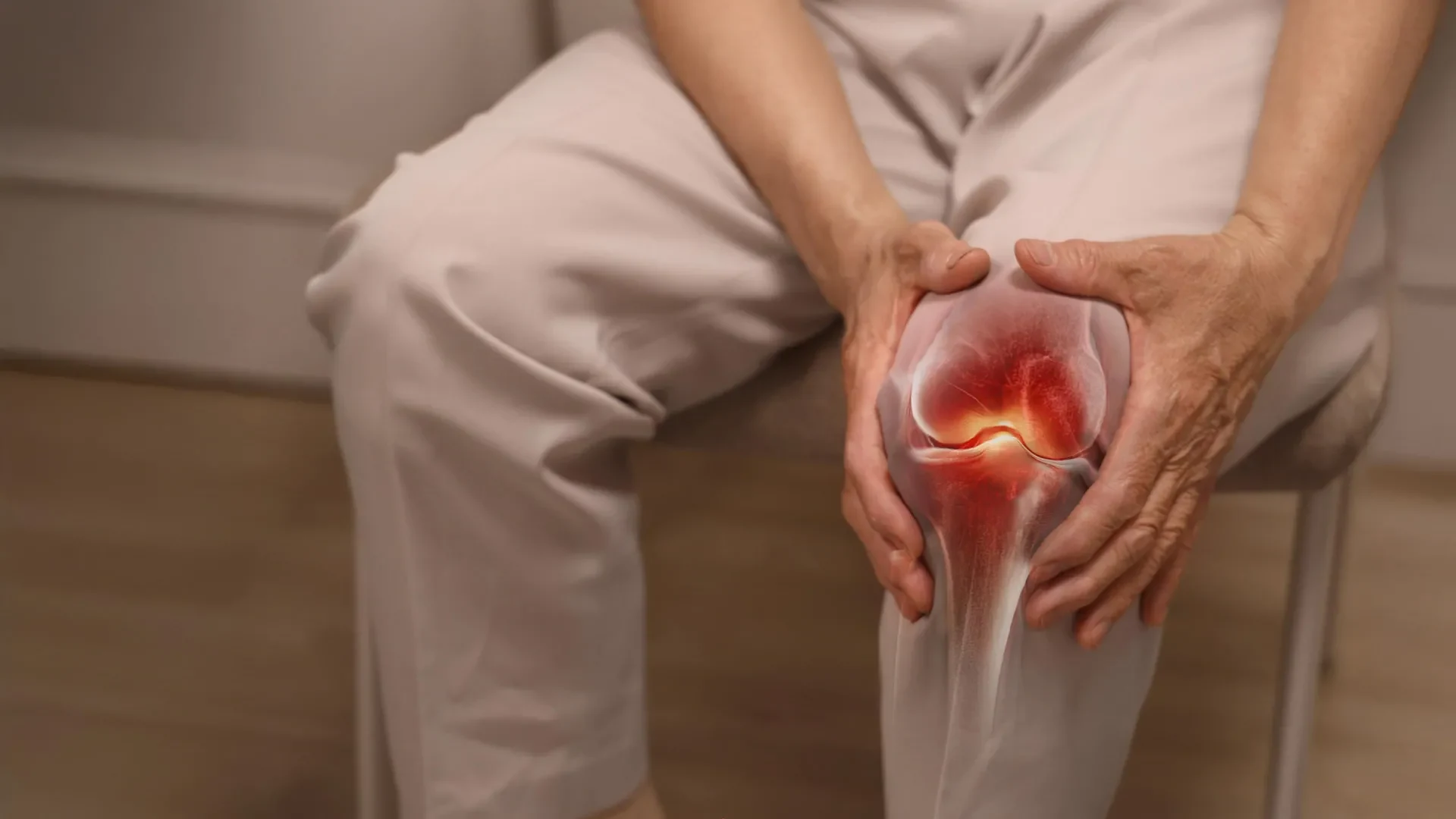 An elderly person sitting and holding their knee in visible discomfort, representing knee pain related to osteoarthritis.