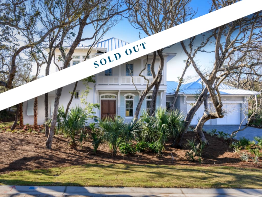 A modern white two-story house with large windows and a wooden front door, surrounded by trees and landscaping, showcases the appeal of new homes in Ponte Vedra Beach, FL—a bold “SOLD OUT” banner stretches across the image.