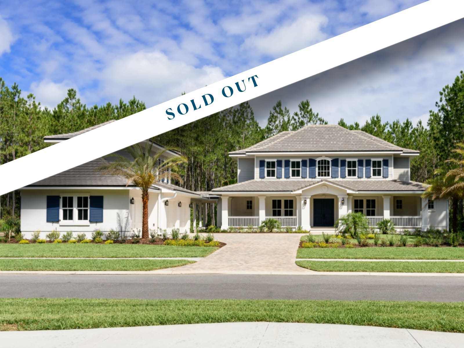 Two large, modern suburban houses with manicured lawns and palm trees, set against a backdrop of trees. A white diagonal banner across the image reads SOLD OUT in bold blue letters—these were premier Ponte Vedra FL new homes.