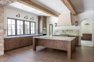 Custom kitchen features including a large center island, natural wood cabinetry and exposed ceiling beams