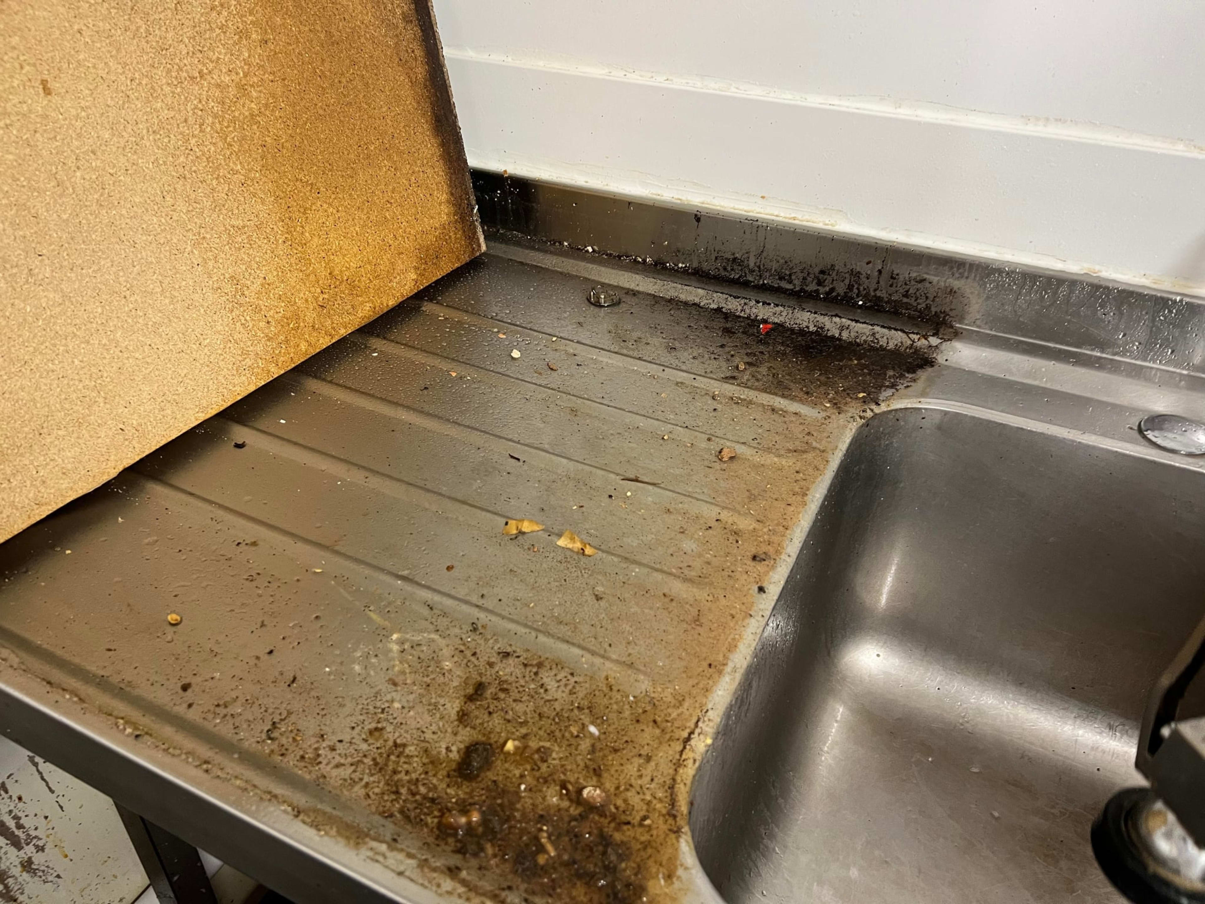 Dirty kitchen sink area before cleaning service.