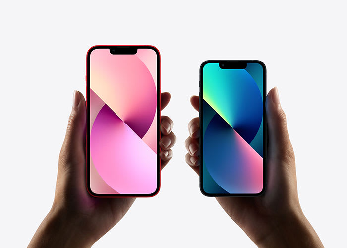 Zwei Hände halten nebeneinander zwei moderne Smartphones mit rahmenlosen Bildschirmen. Das linke Handy hat einen roten Rahmen und zeigt ein abstraktes Hintergrundbild in Rosa- und Lila-Tönen. Das rechte Handy hat einen schwarzen Rahmen und ein Hintergrundbild in Blau- und Grüntönen. Beide Bildschirme sind eingeschaltet und zeigen keine weiteren Details oder Apps.