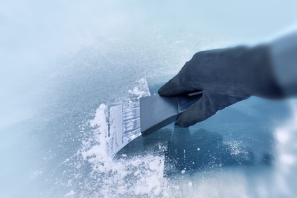 winter driving - scraping ice from a windshield