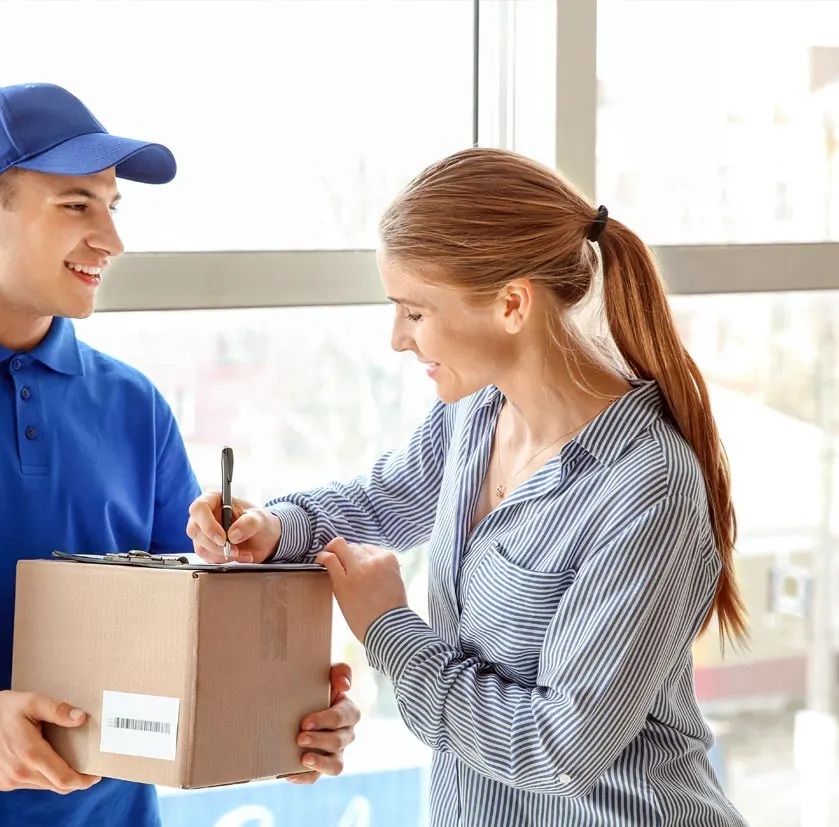 Woman signing paper and man holding a delivery package