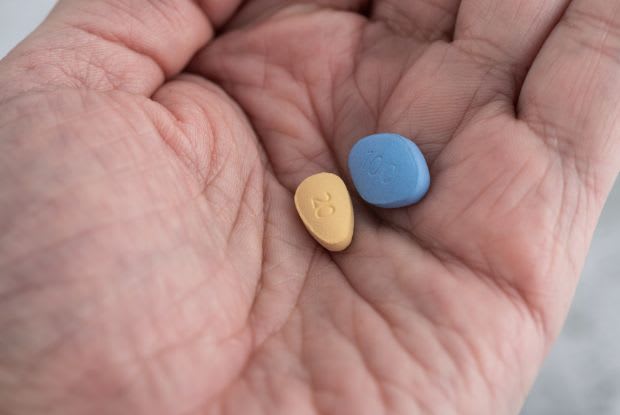 a hand holding a Cialis and Viagra pill