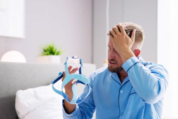 a frustrated man holding a CPAP mask