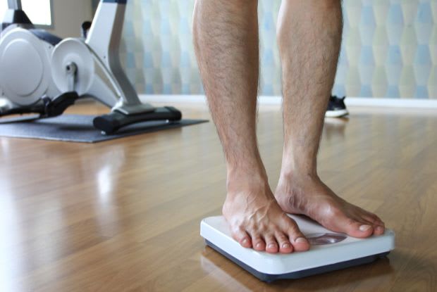 A man standing on a scale in the gym
