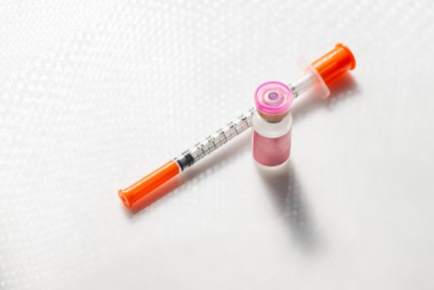 A vial of medication next to a needle