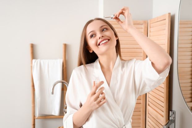A woman applying minoxidil to her scalp