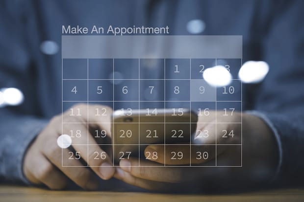 A graphic of a person booking an appointment from a mobile device with a translucent calendar overlaid. 