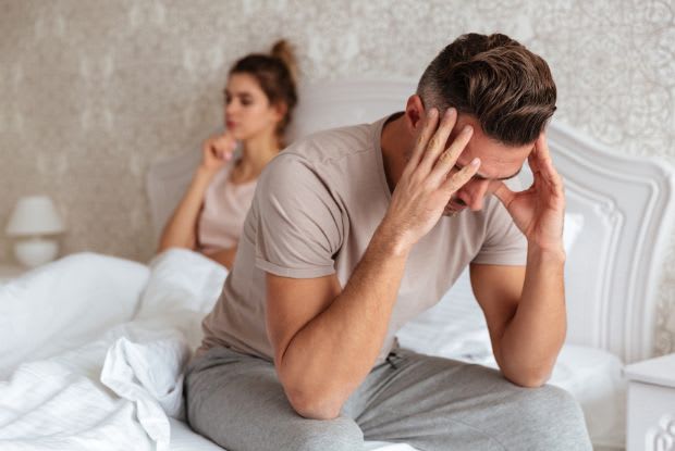 a frustrated man sitting in bed